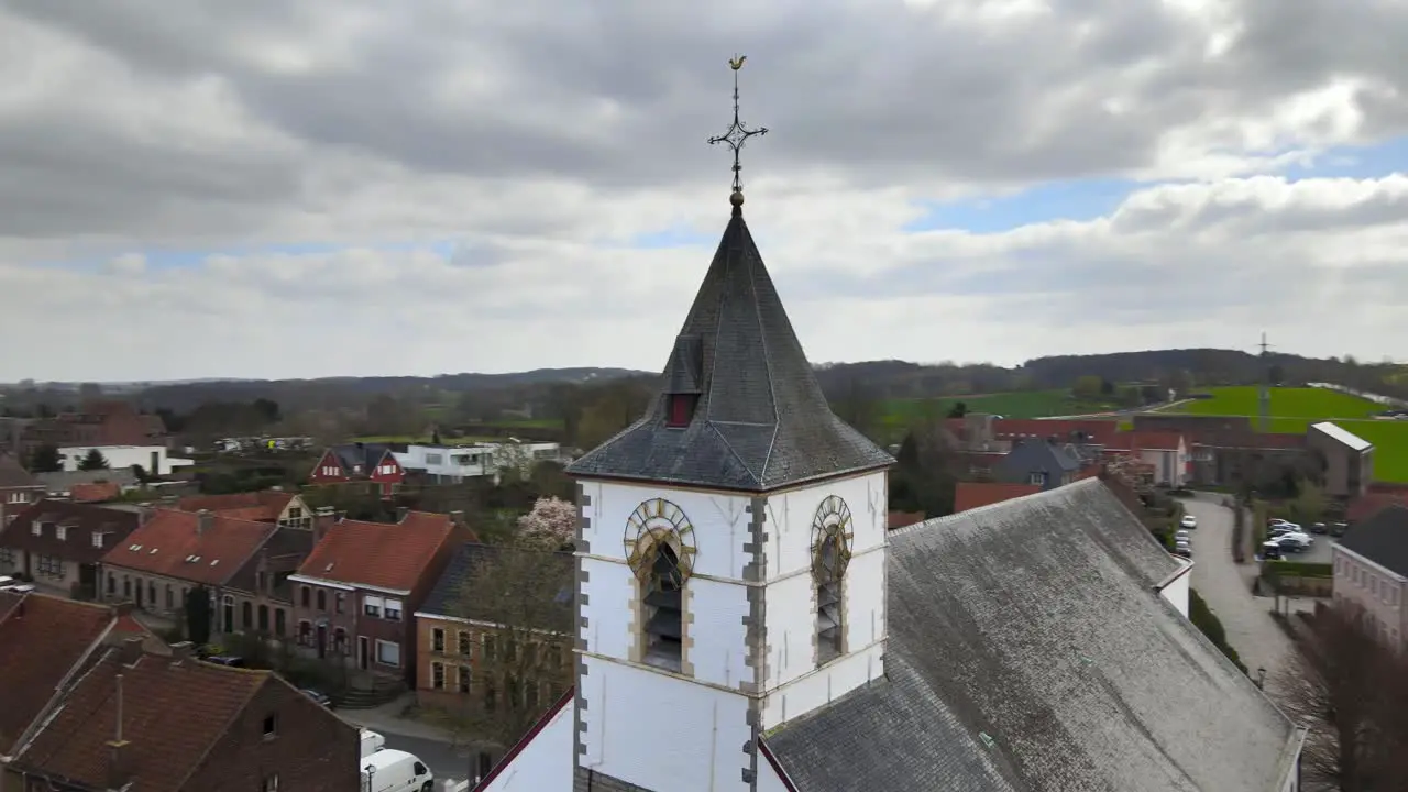 Aerial drone counter rotation around church clock with Belgian hills in the background