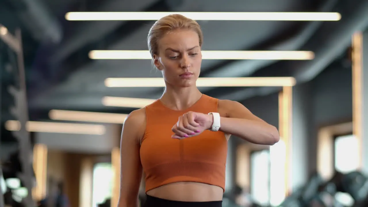 Tired athlete girl checking results at gym Sportswoman standing in sport club