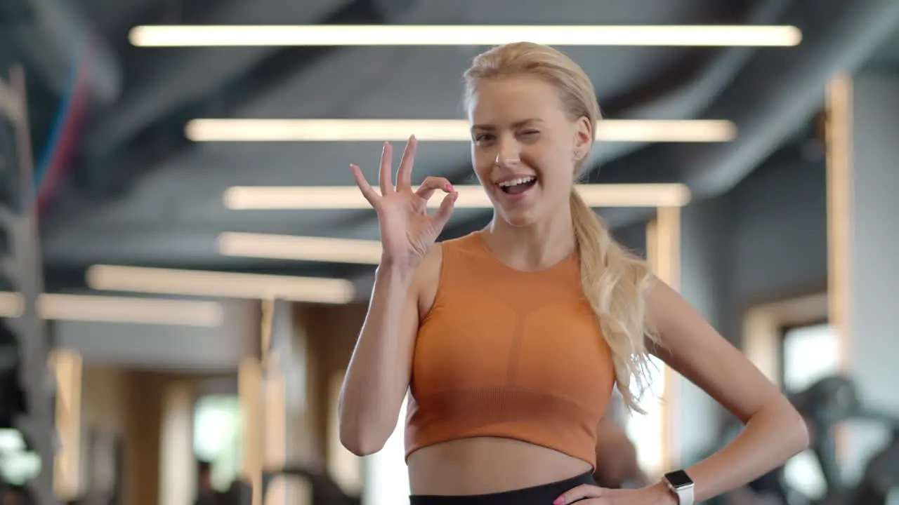 Cheerful athlete girl showing ok sign at gym Sportswoman standing in sport club