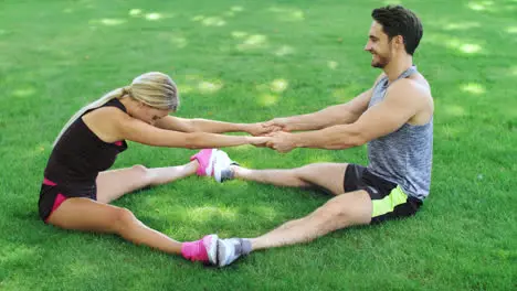 Fitness trainer help woman stretching legs at warm up training in park