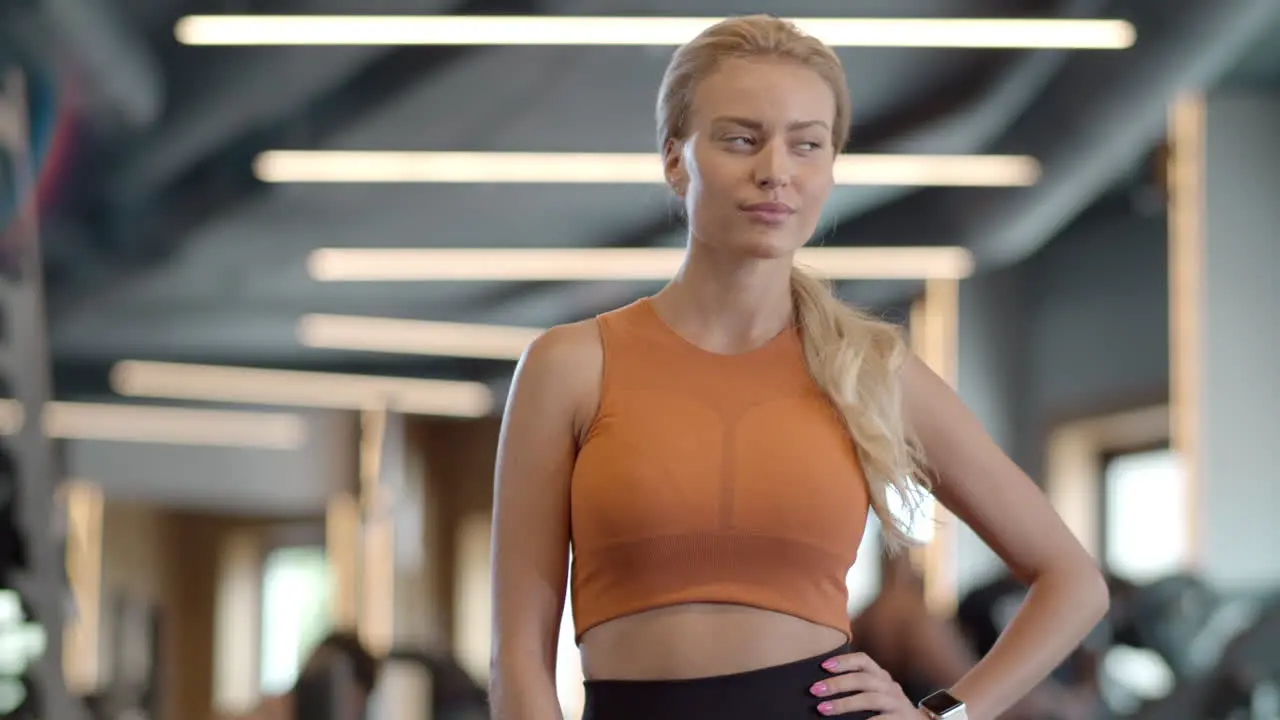 Smiling female athlete in fitness center Fitness woman standing at gym