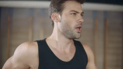 Closeup handsome man running on treadmill machine in fitness club