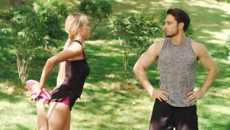 Fitness couple warm up together before training in summer park