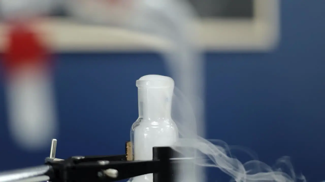 In a methodical slow-motion closeup a test tube reveals a distinct chemical reaction as white vapors ascend epitomizing the precision and complexity of laboratory research