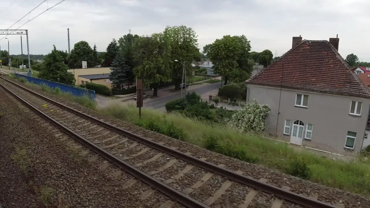 A view of the buildings Wolin station and the trees from a moving train