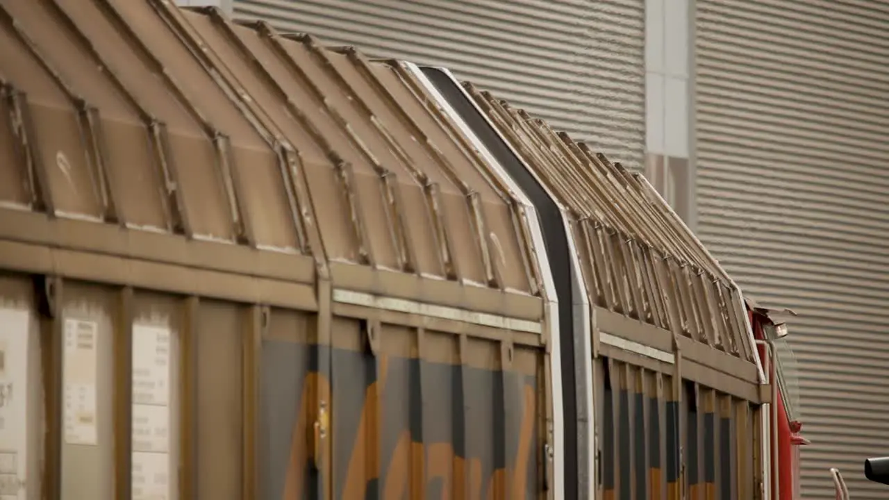 Side view of a driving rusty train carriage focusing on the roof structure