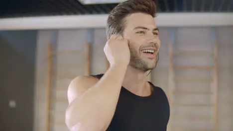 Portrait of handsome runner listening music on treadmill machine in fitness club