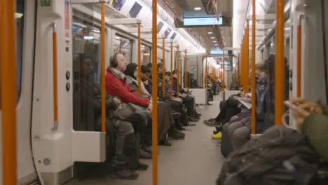 Interior Shot Of Passengers Commuting In Carriage Of UK Train In Early Morning