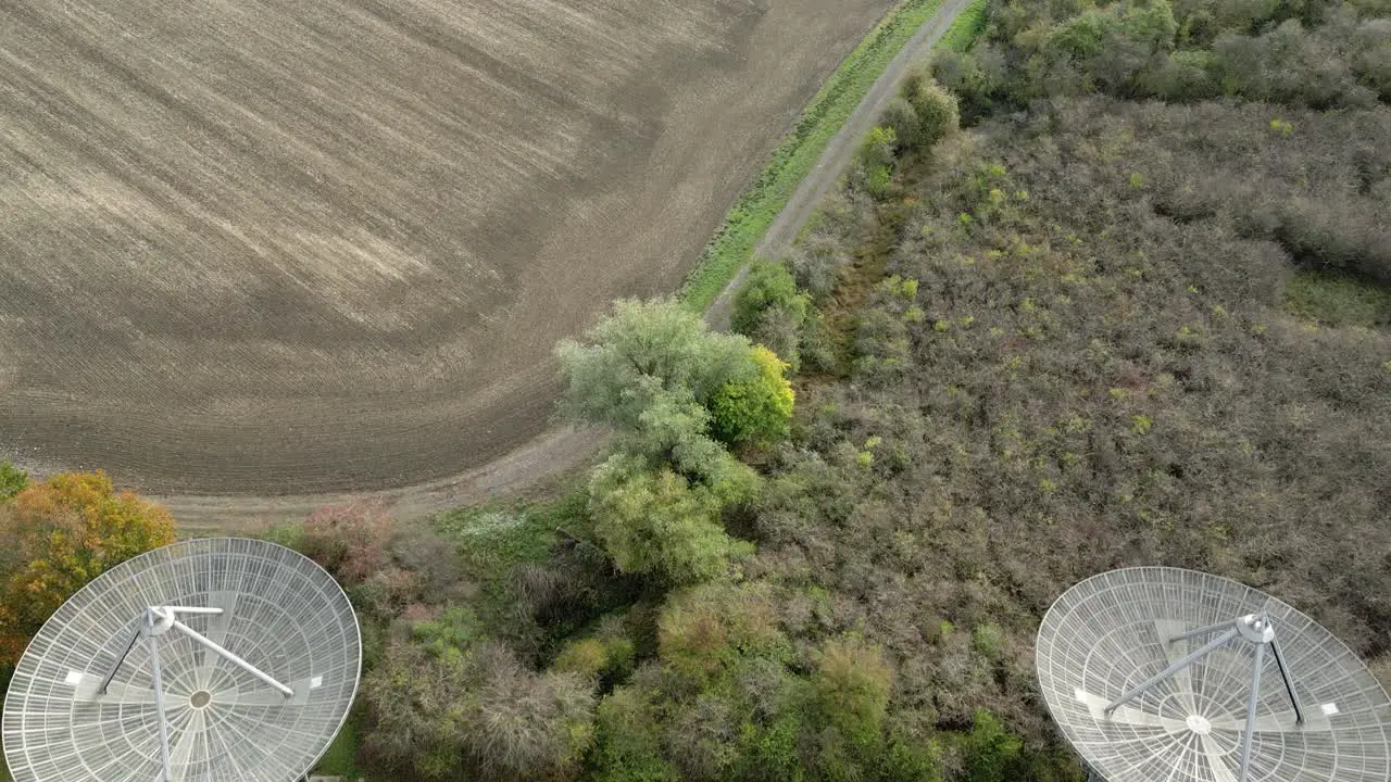 Aerial view above agricultural farmland and Mullard MRAO radio observatory telescope array