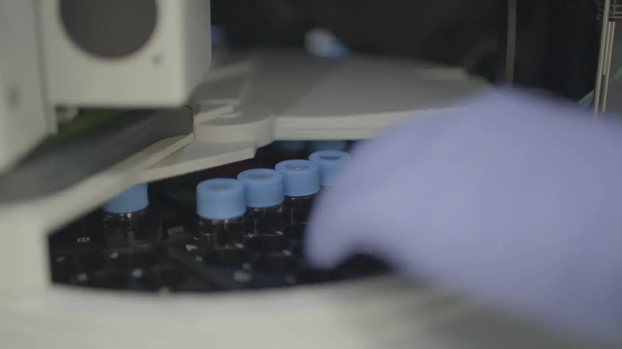 Lab equipment spinning test tubes with researcher grabbing tube tray