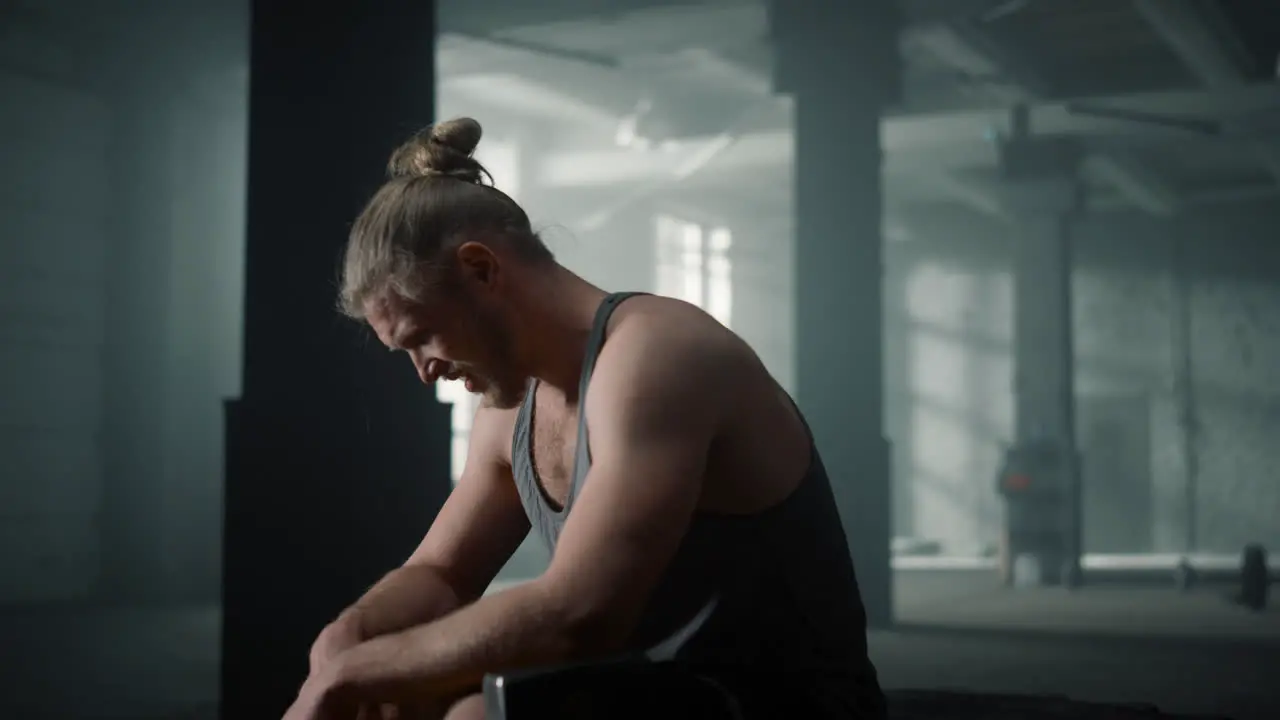 Sportsman sitting on crossfit tire Fitness man taking break between exercises