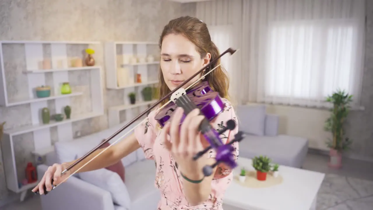 Violinist young woman playing her purple violin at home