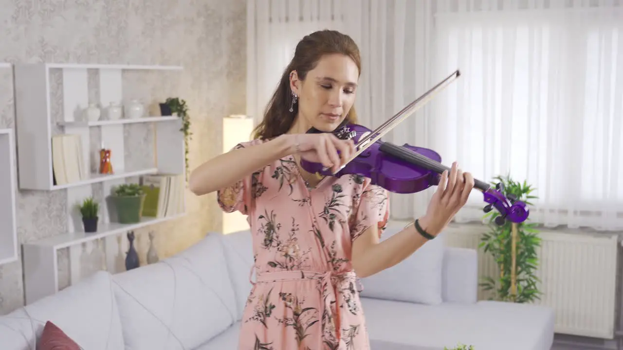 Talented musician woman playing violin in living room at home