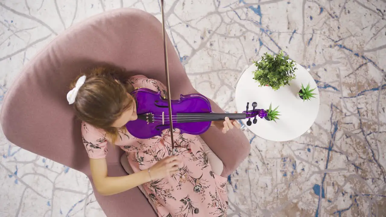 Musician Woman sitting on sofa at home and playing violin