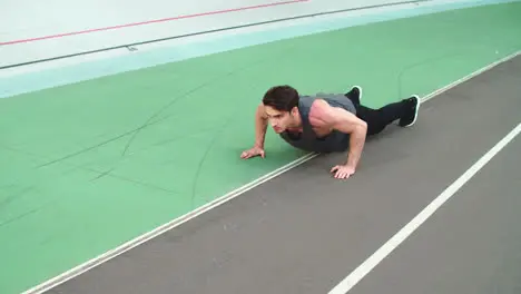 Fitness man doing push ups in slow motion at stadium outdoor