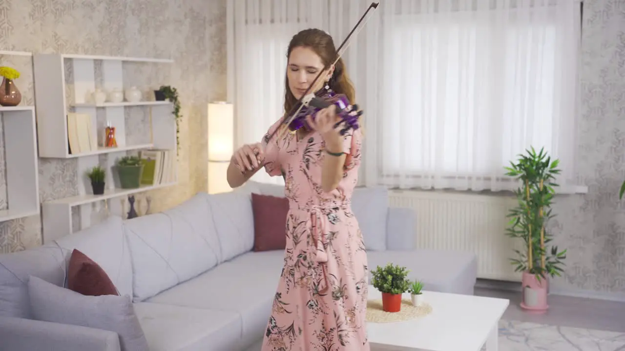 Elegant woman playing the violin in the living room at home rests her soul