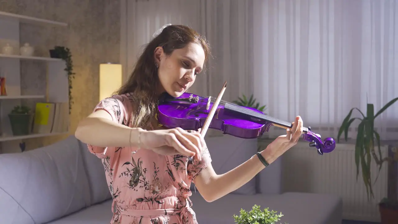 Young girl plays the violin in the living room