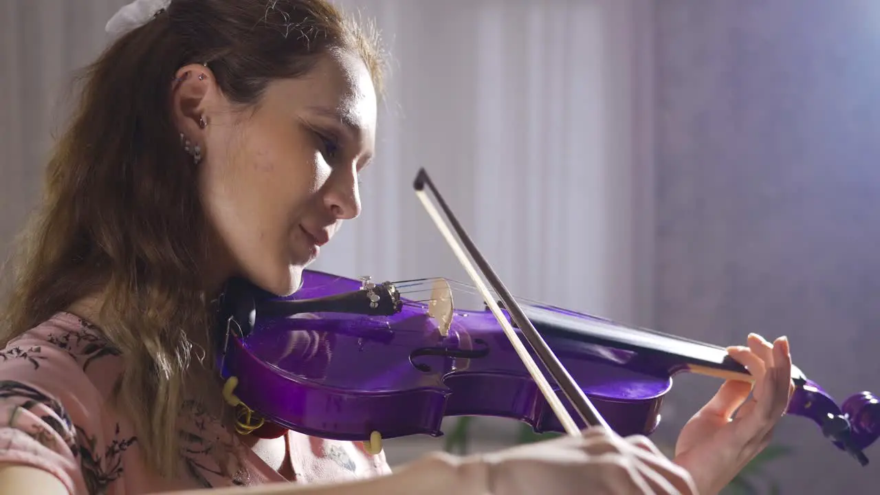 Violinist young woman playing violin at home close-up