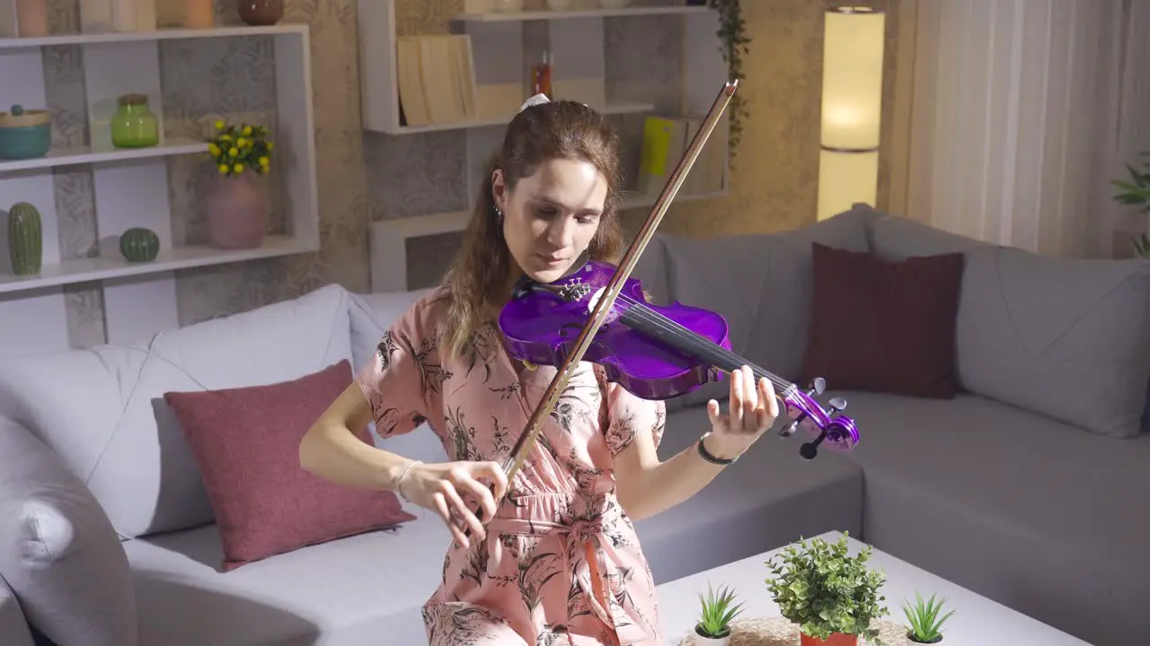 Young woman playing the violin alone in the living room at home