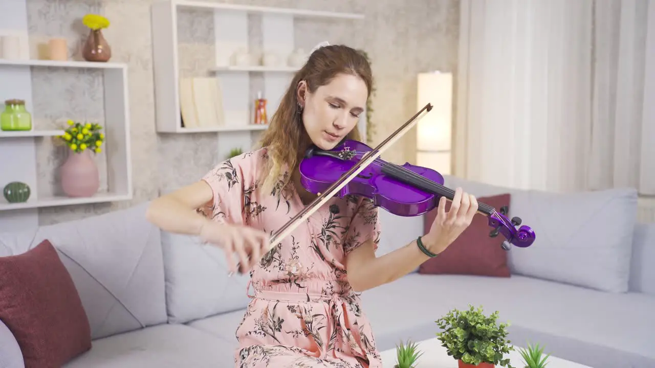 Young musician woman playing her violin at home composing songs producing