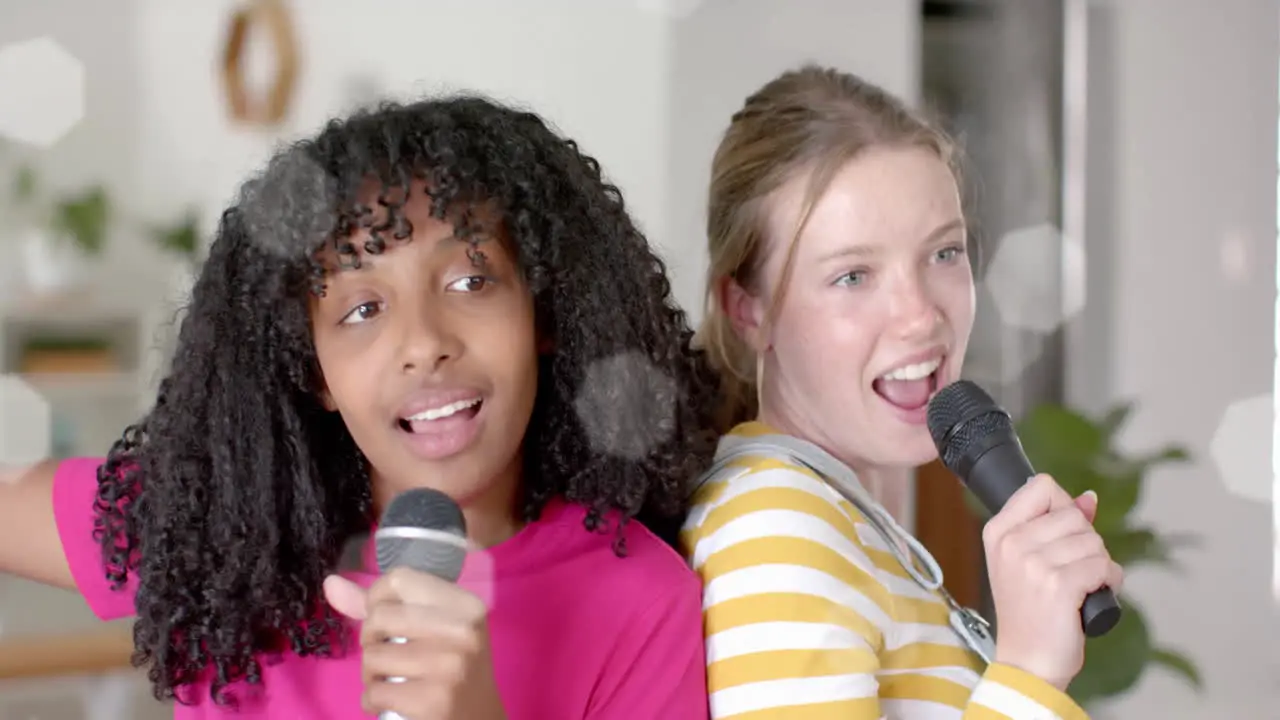 Animation of white lights over happy diverse teenage girls with microphones singing karaoke at home