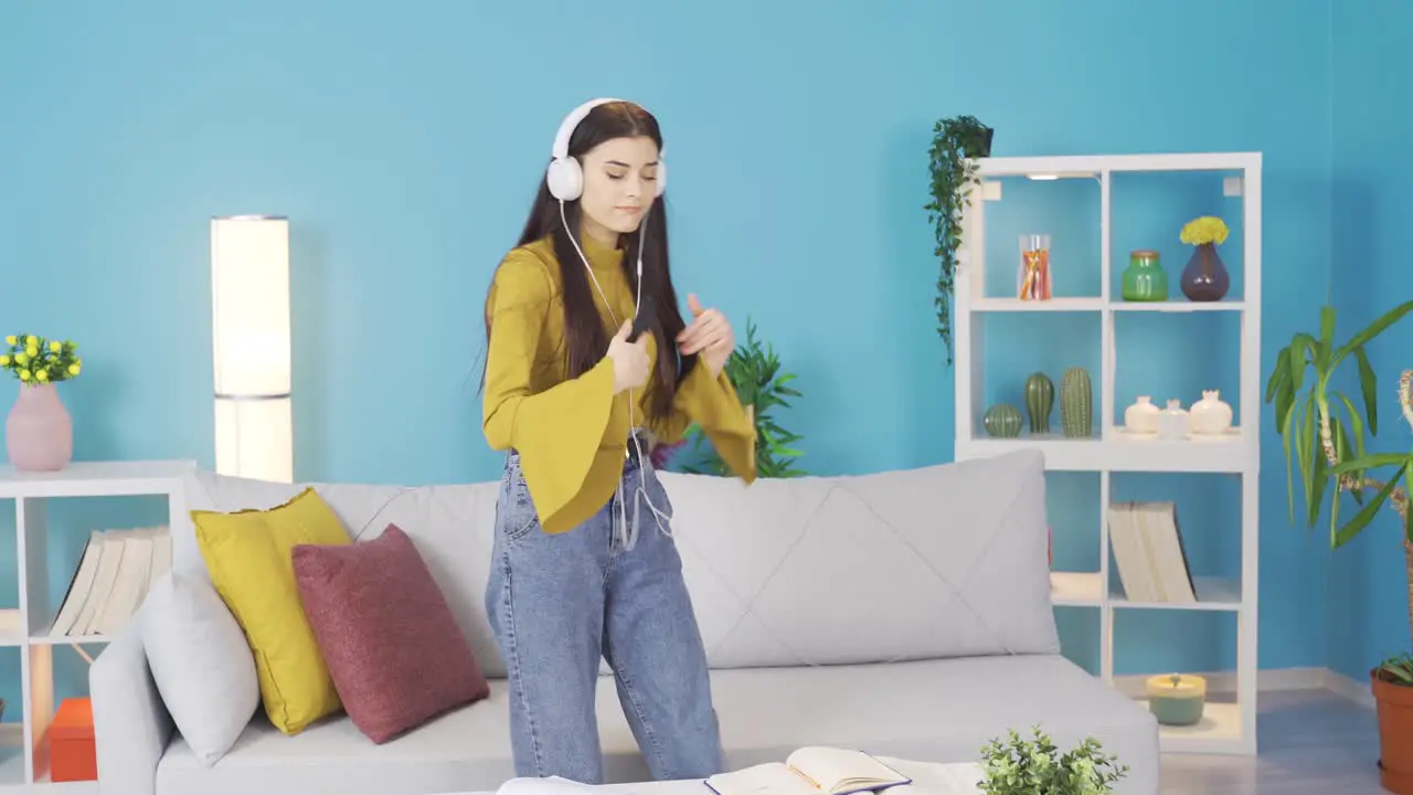 Happy and cute young woman listening to music and dancing at home