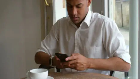 Tilt Up Male customer sitting in cafe using smartphone