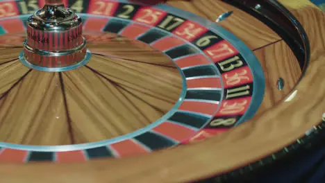 Closeup of wooden roulette wheel rotating in foreground Table in luxury casino