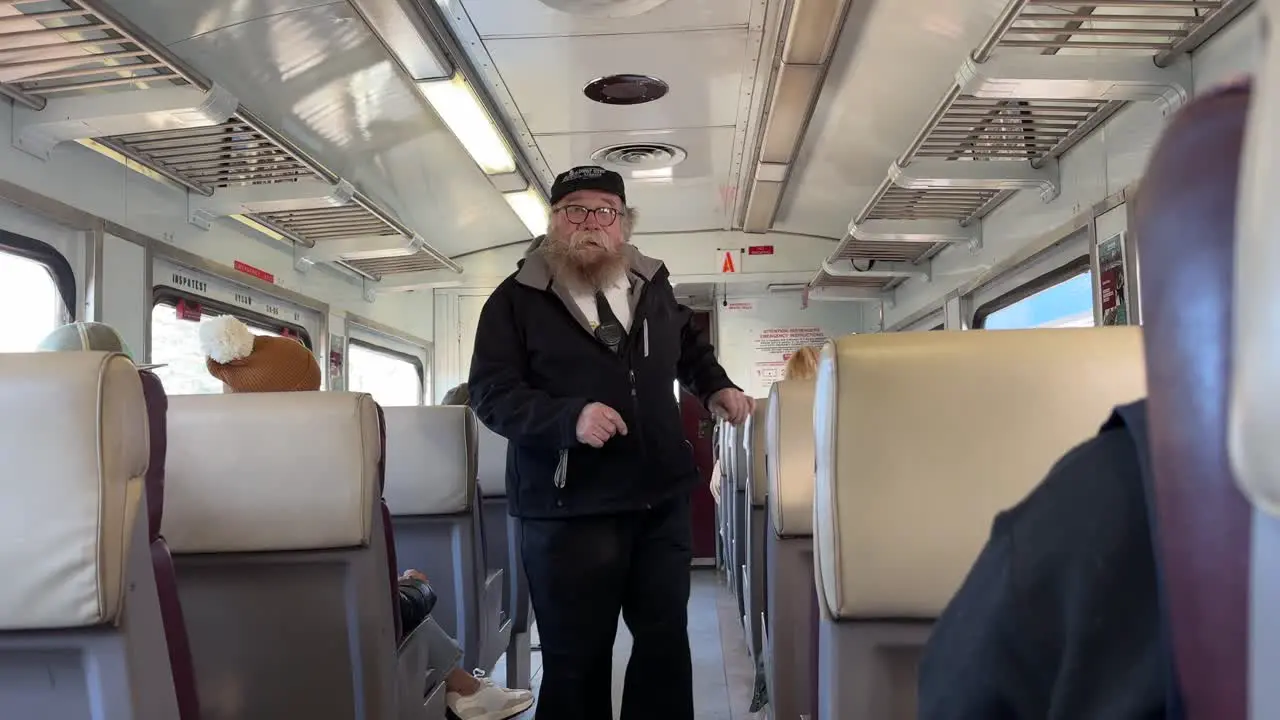 Train conductor or guard walks through carriage checking tickets