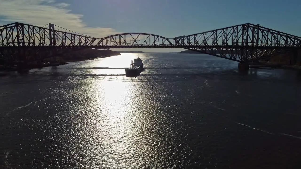 Drone shot going backward while a cargo boat is travelling under Quebec bridge