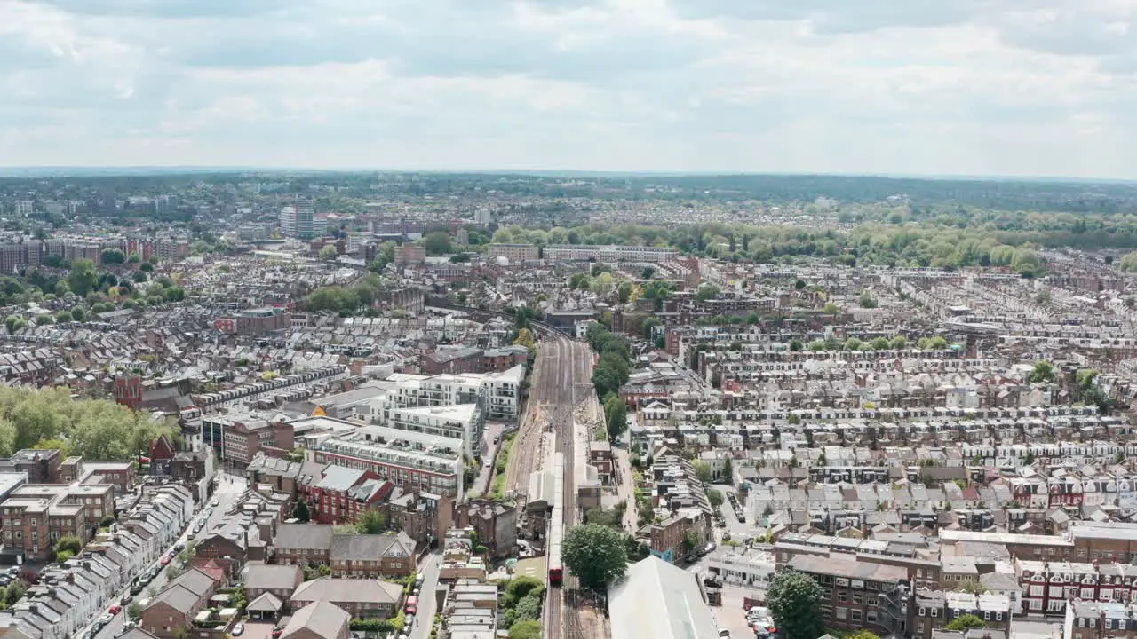 Descending drone shot of district line train arriving at Parsons green station London