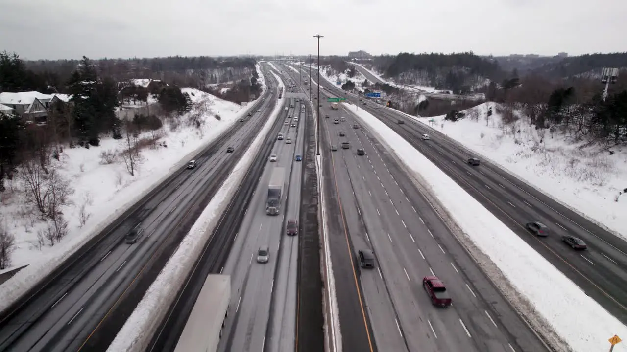 Tracking Aerial Flyover of Busy Winter Highway with blowing Snow and transport trucks in Scarborough Toronto East 401 Overcast Day