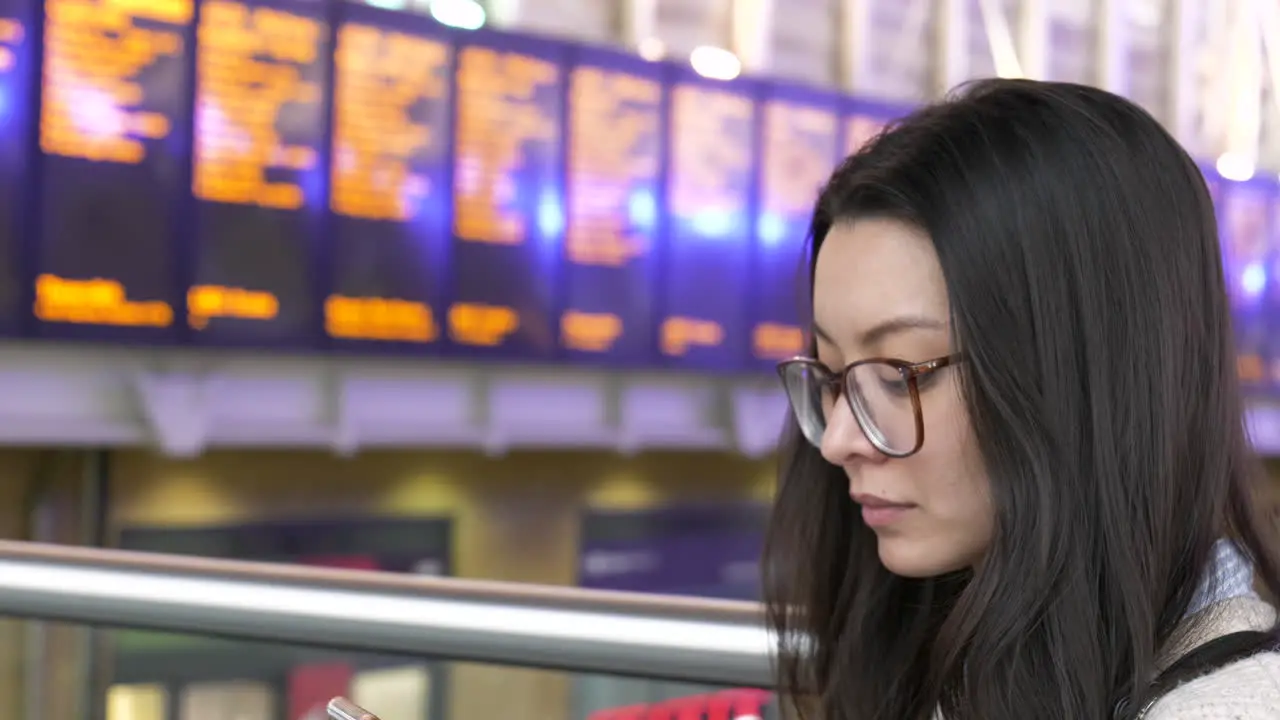 Woman waiting for a train checks her phone for times and tickets before traveling