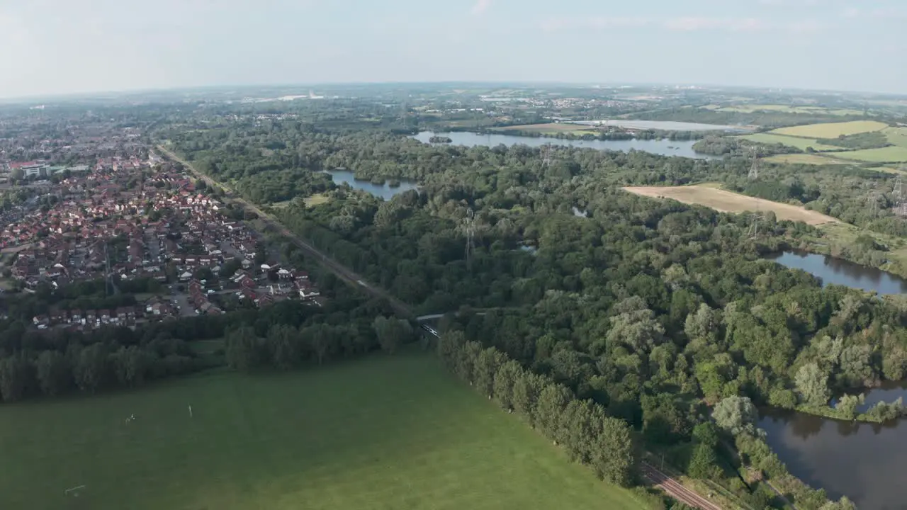 Profile follow drone shot of National rail train passing through British countryside village