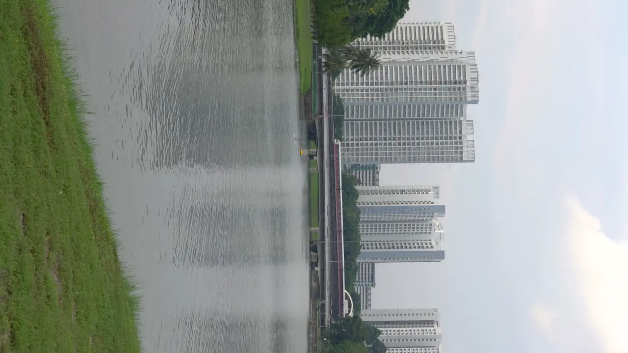 Vertical video someone kayaking at the distance  train passing by Singapore