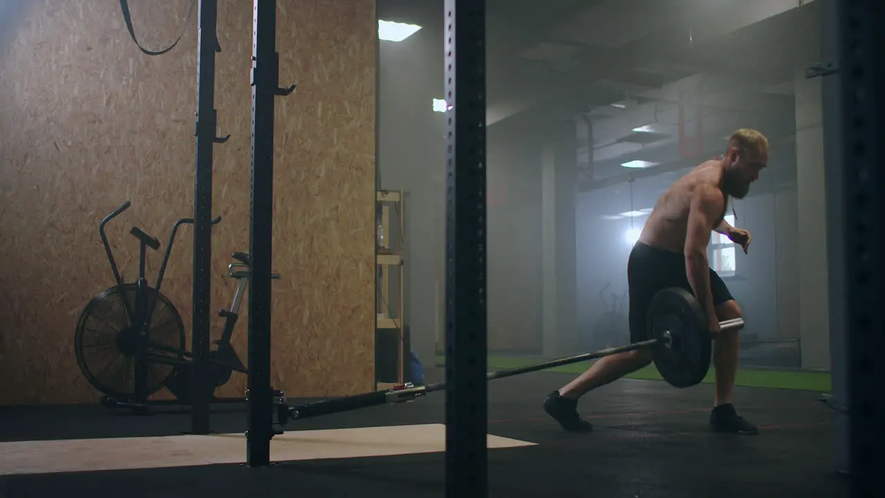 Slow motion Man doing Single-Arm Landmine Squat-to-Press exercise Young man lifting barbell with light weights at gym