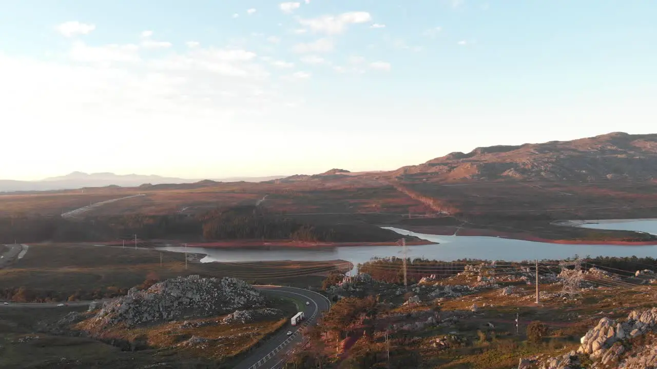 A drone shot showing a lakeside road at sunset