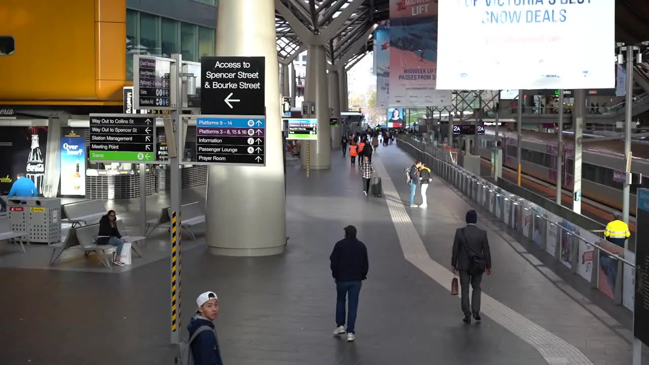 Footage of Inside Melbourne Iconic Southern Cross Station pathway with directory signage and passerby wondering