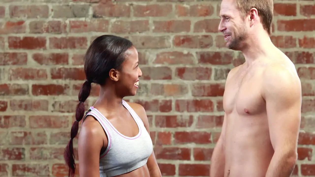 Fit couple talking in crossfit gym