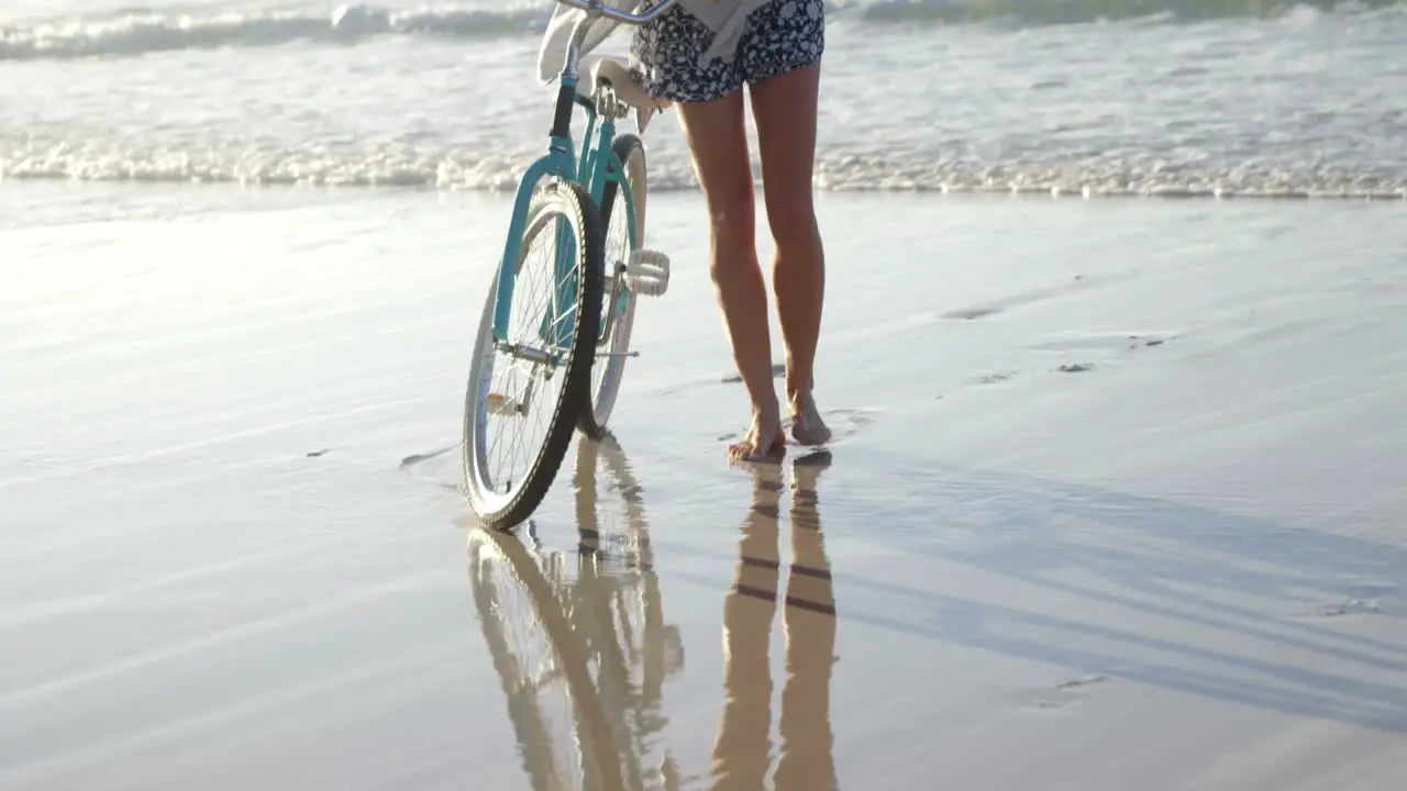 Woman standing with her bicycle at beach