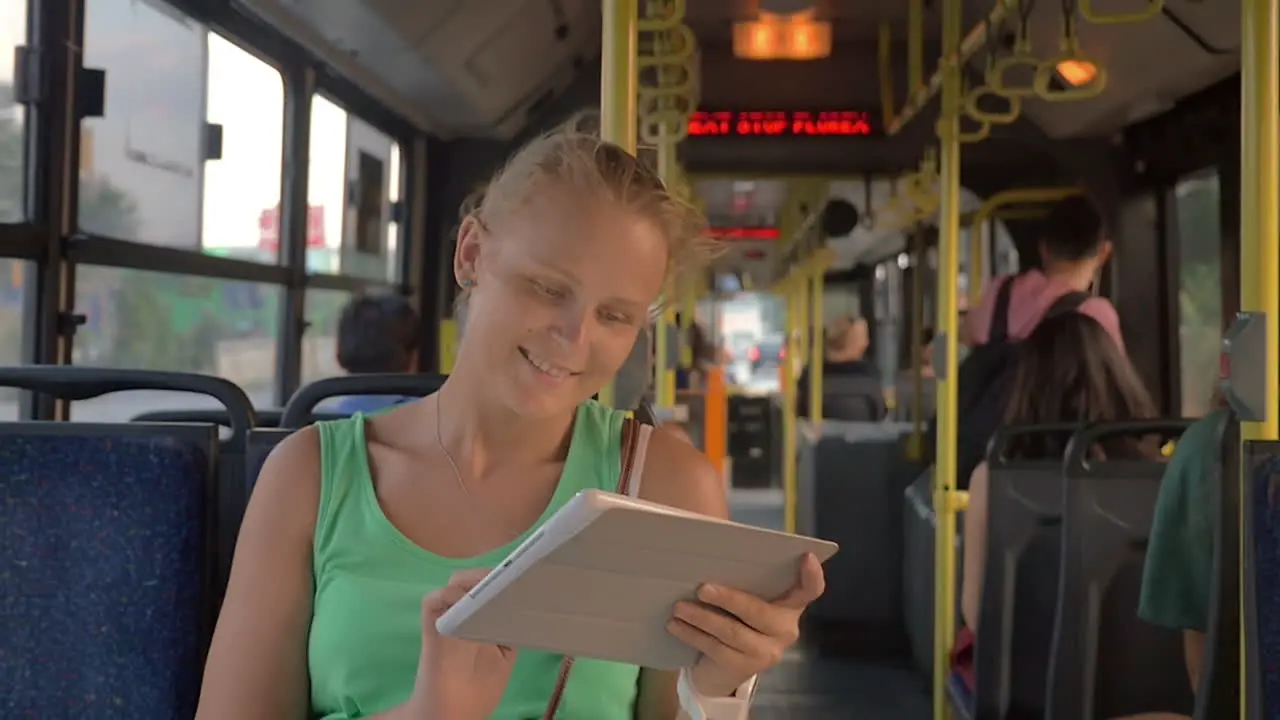 Smiling Woman Typing in Tablet in the Bus