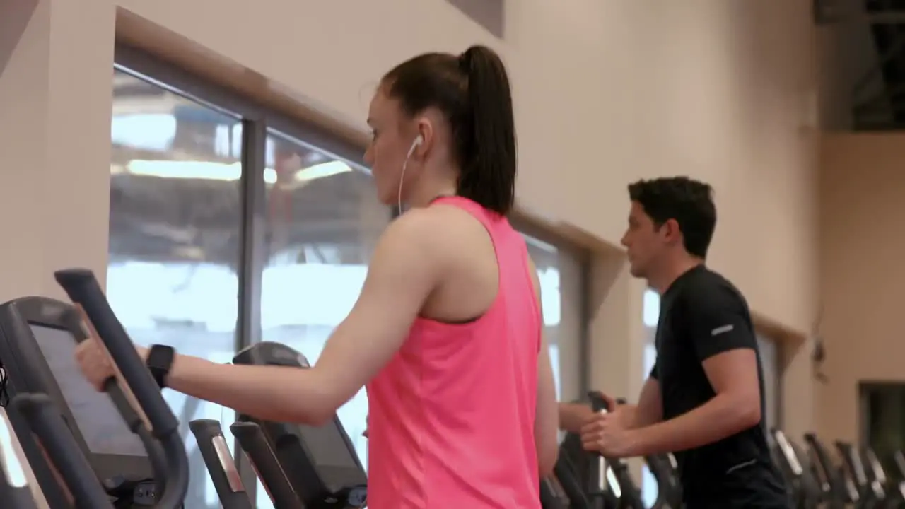 Man and woman using the cross trainers in gym