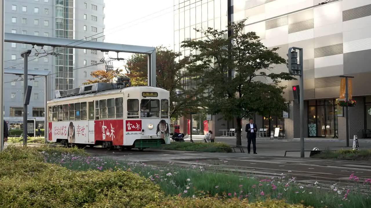 Vintage Tram Approaching Toyama Station As Person Walks Across Crossing