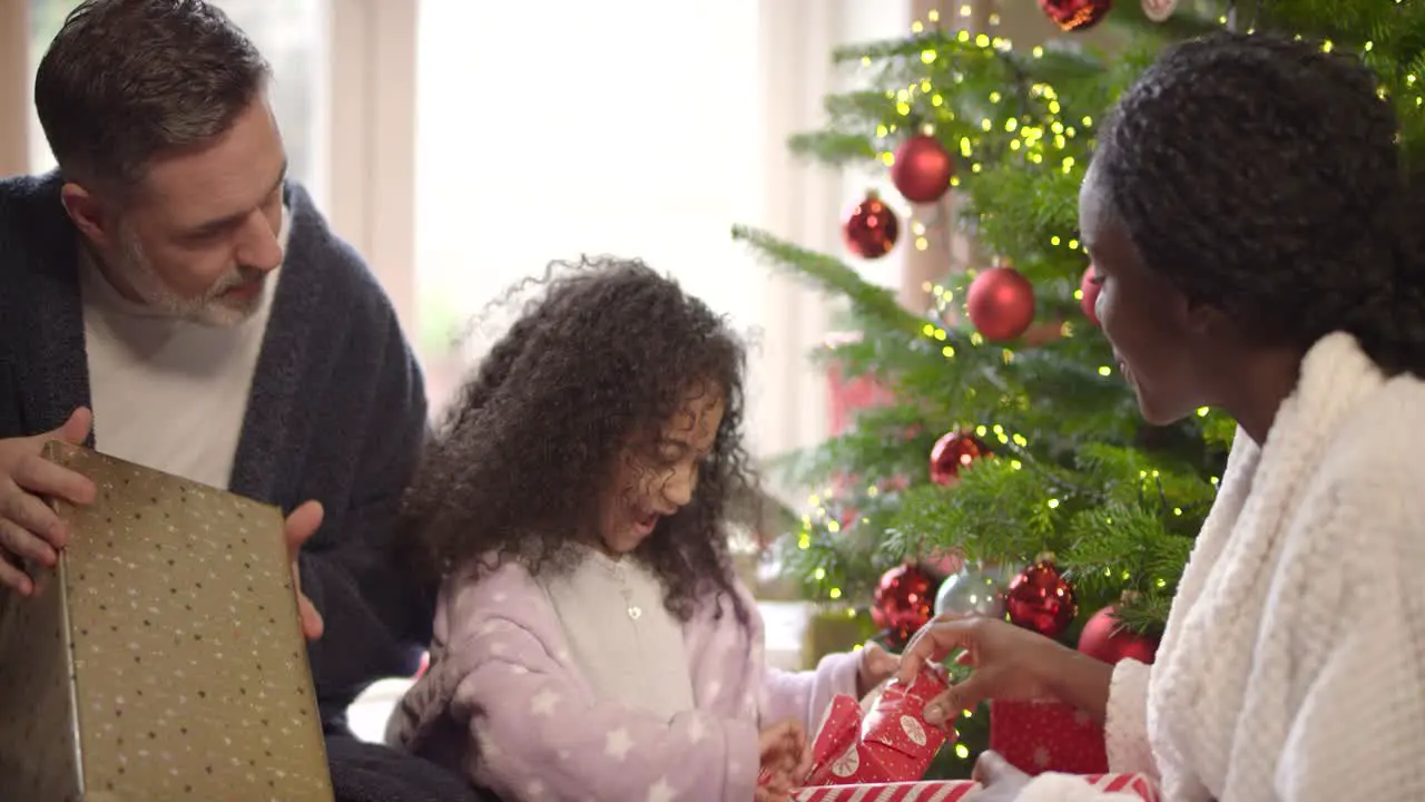 Child Unwrapping Present with Parents