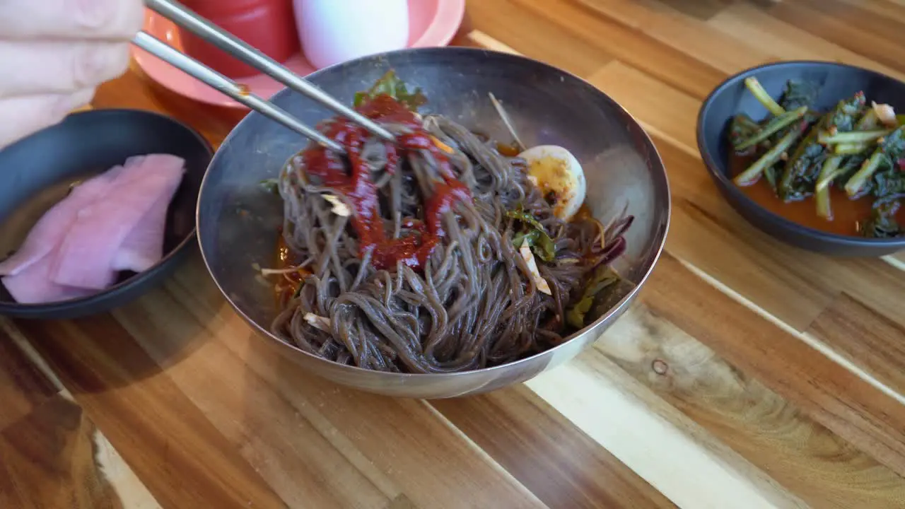 Adding Gochujang To Korean Buckwheat Noodles And Mix With Chopsticks Chuncheon City South Korea close up high angle