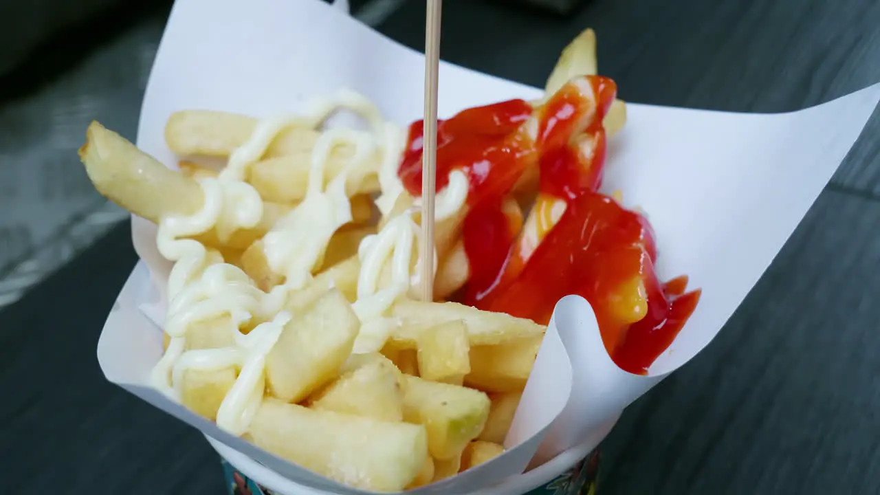 Hot french fries drop on white paper for absorb oil after cooking and pouring salt scatter with sauce