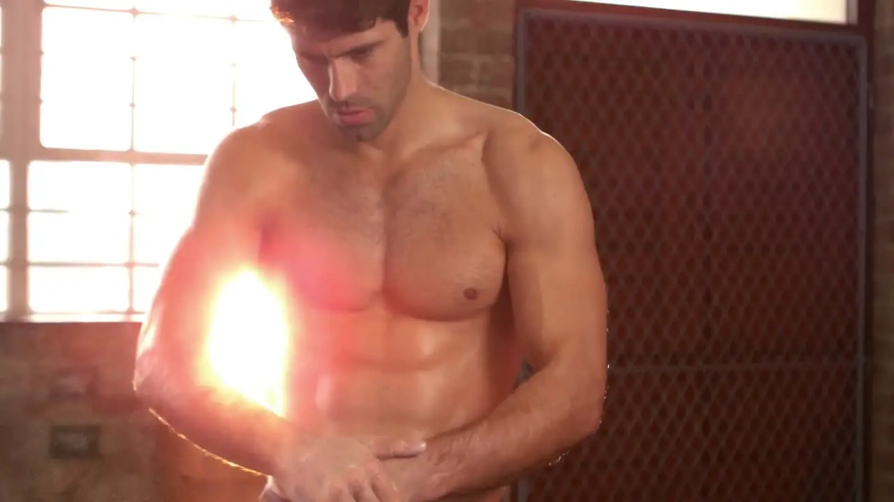 Fit man chalking his hands in gym