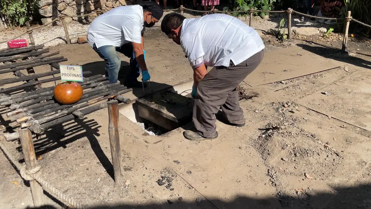 slow motion shot of chefs removing cochinita pibil from the ground oven in merida yucatan