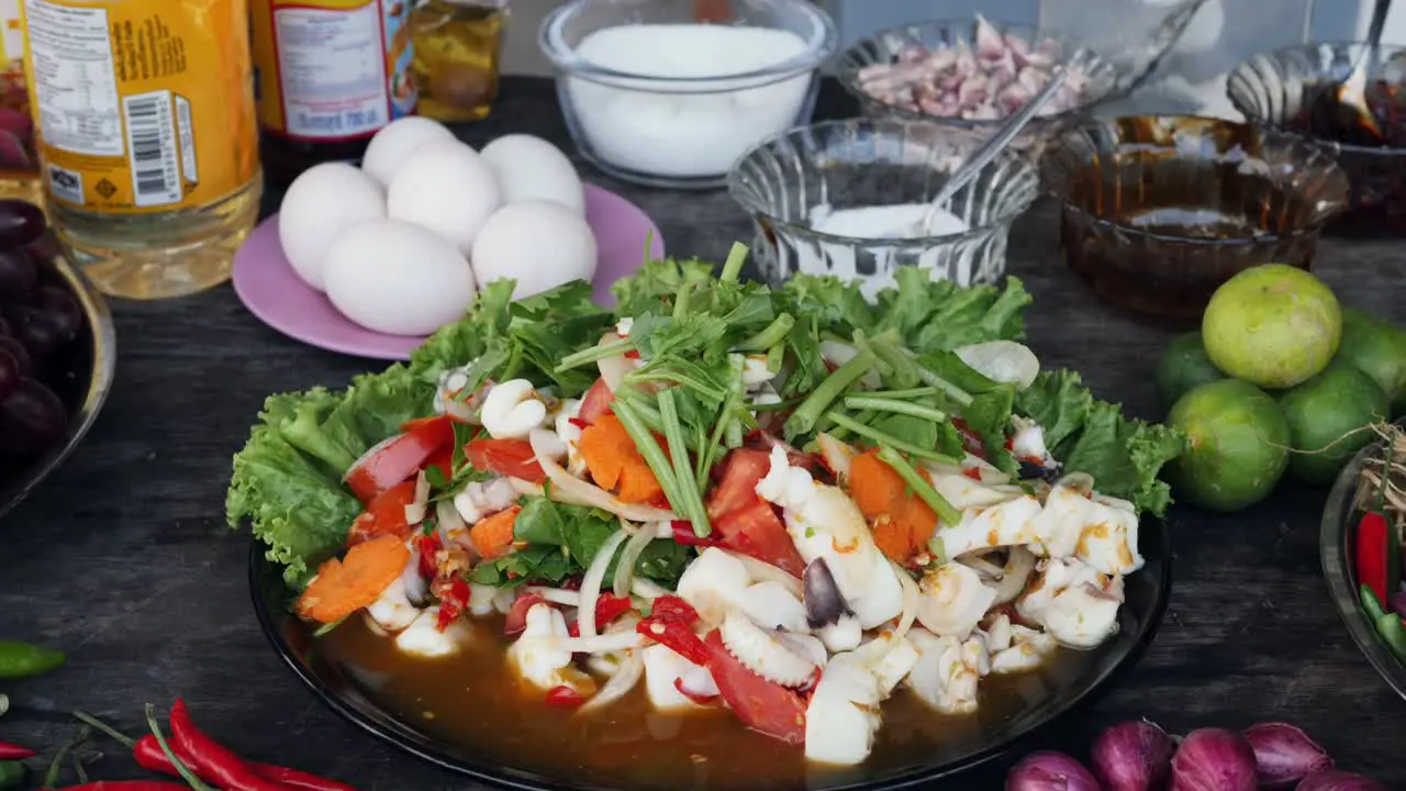 Close up of squid and vegatable dish on table surrounded by ingredients