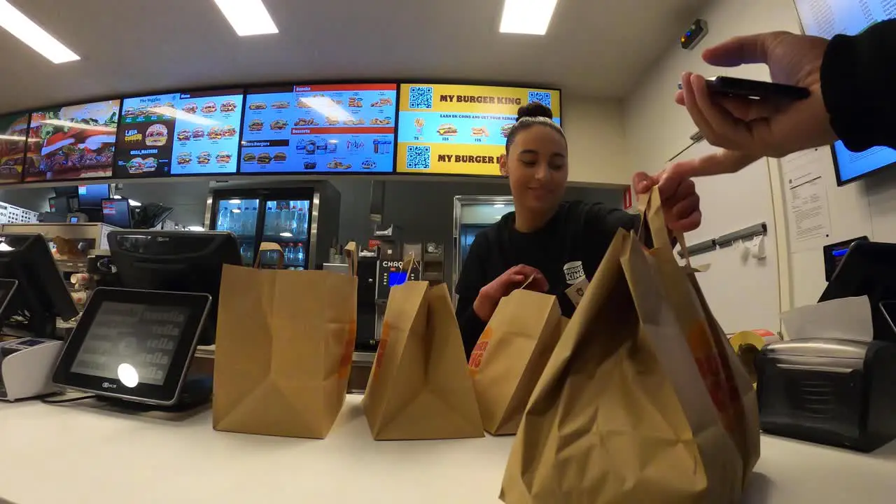 Burger King's employee giving takeaway food bag to delivery courier